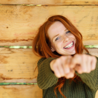 lachende frau im grünen strickpullover zeigt mit dem finger nach vorne lachende frau im grünen strickpullover zeigt mit dem finger nach vorne
