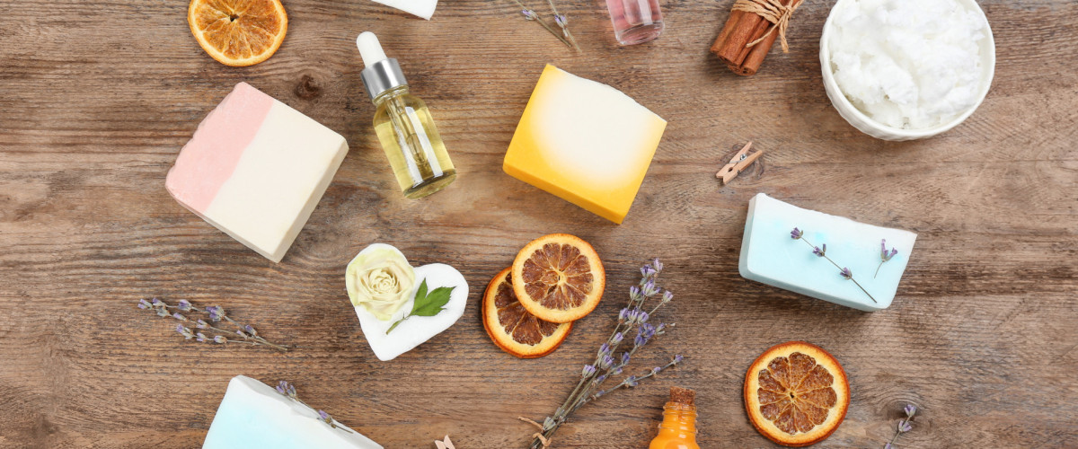 Handgemachte Naturseifen mit Pflanzenölen, Lavendel und getrockneten Orangenscheiben auf einem Holztisch.