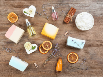 Handgemachte Naturseifen mit Pflanzenölen, Lavendel und getrockneten Orangenscheiben auf einem Holztisch.